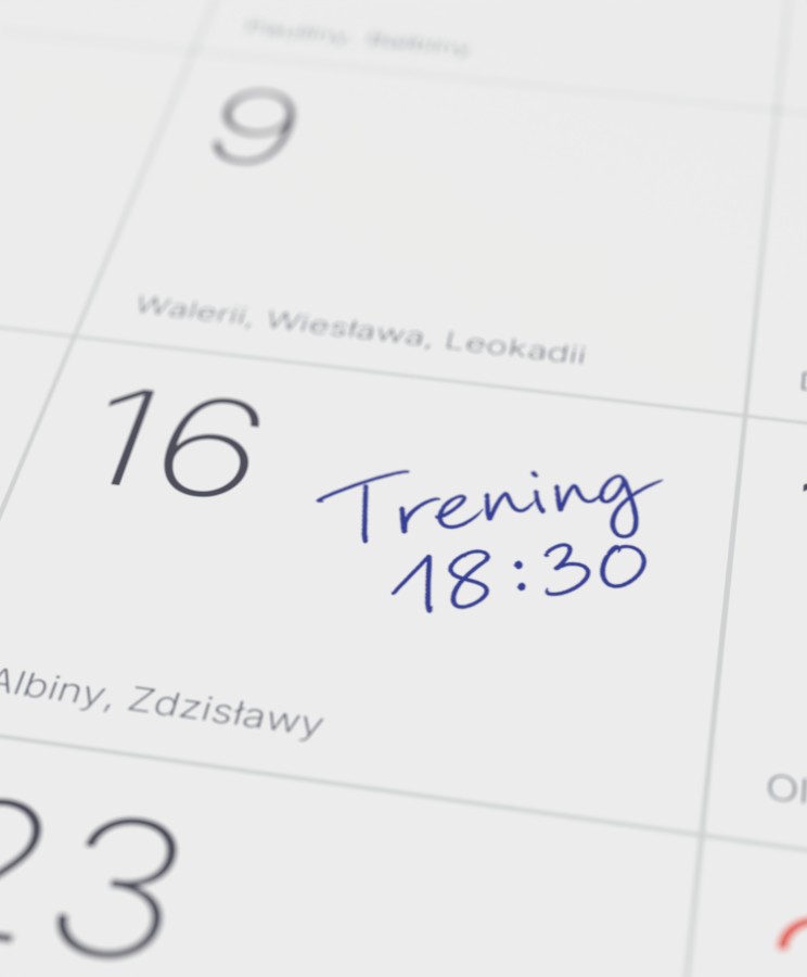 Zbliżenie kalendarium z&nbsp;odręcznym wpisem „Trening 18:30” w&nbsp;polu dnia